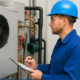 Worker in blue hard hat inspecting HVAC equipment using clipboard in a professional setting.